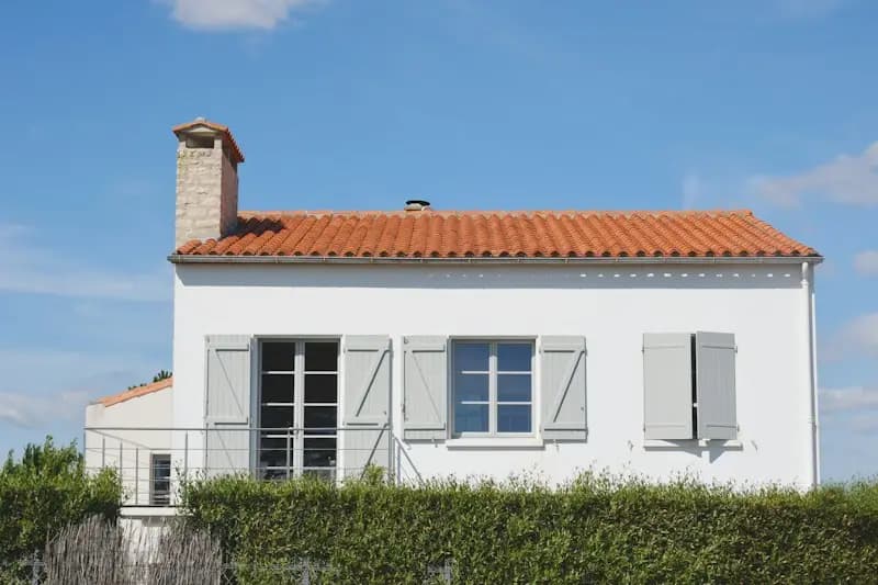 Maison blanche aux volets gris et toit de tuiles