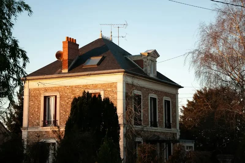 Maison ancienne en brique et pierre entourée d'arbres