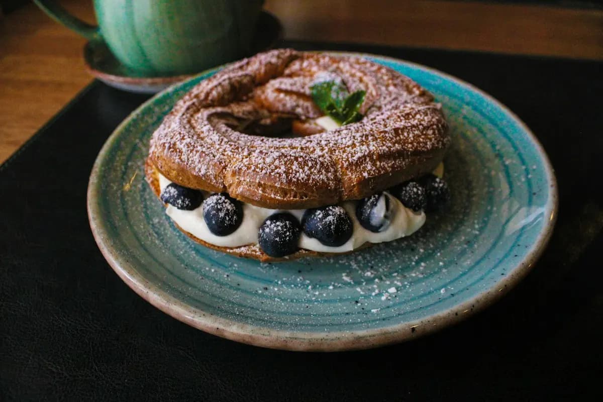 Paris-Brest garni de myrtilles sur une assiette bleue