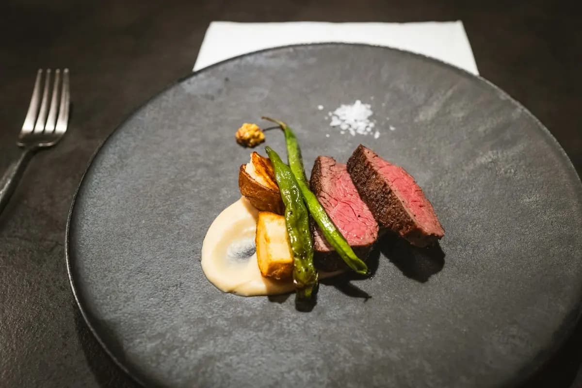 Filet de bœuf, haricots verts et purée, dressés sur une assiette sombre