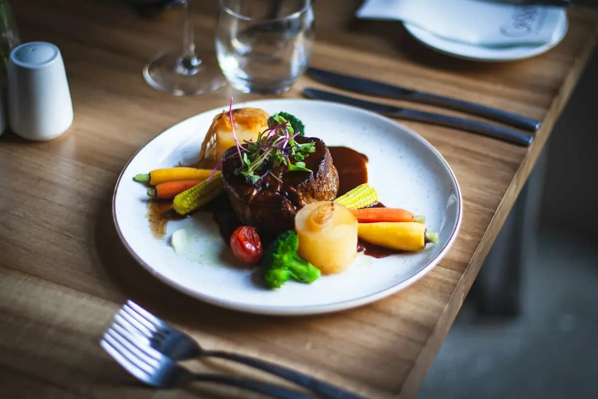 Assiette dressée sur une table en bois, couverts et verres